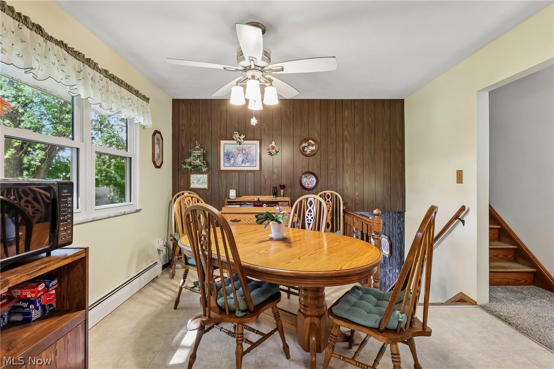 2428 Antioch Road Perry, OH 44081 - Photo 20 of 46 Dining area featuring a wood-panel accent wall, overhead ceiling fan with integrated lighting, and light-toned flooring