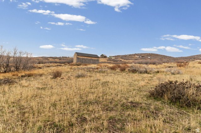 349 West Mountain View Road, Unit 349 Fairview, UT 84629 - Photo 19 of 26 Expansive rural landscape featuring a prominent wooden outbuilding with a dark shingled roof, dry native grasses, scattered brush, and distant rolling hills
