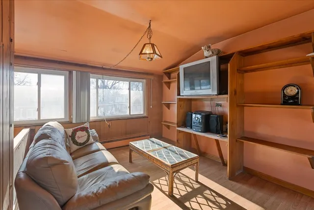 a living room with furniture a large window and wooden floor