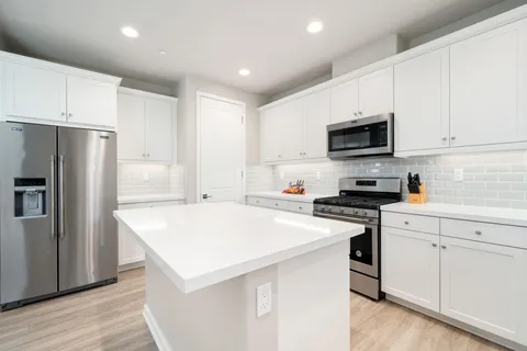 a kitchen with kitchen island a white cabinets and refrigerator