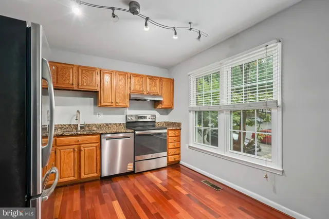 a kitchen with stainless steel appliances granite countertop hardwood floor sink stove and granite counter top