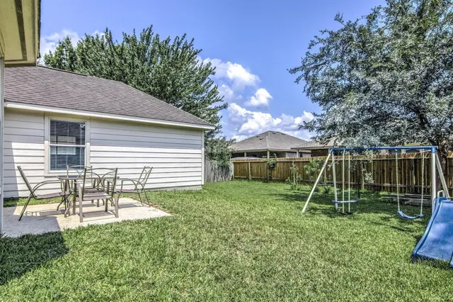 a view of a backyard with a slide trees and wooden fence