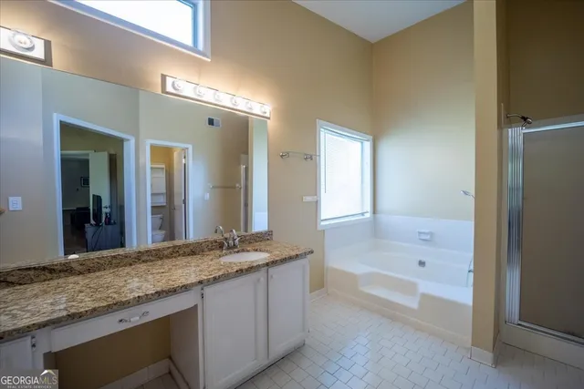 a bathroom with a granite countertop sink and a bathtub