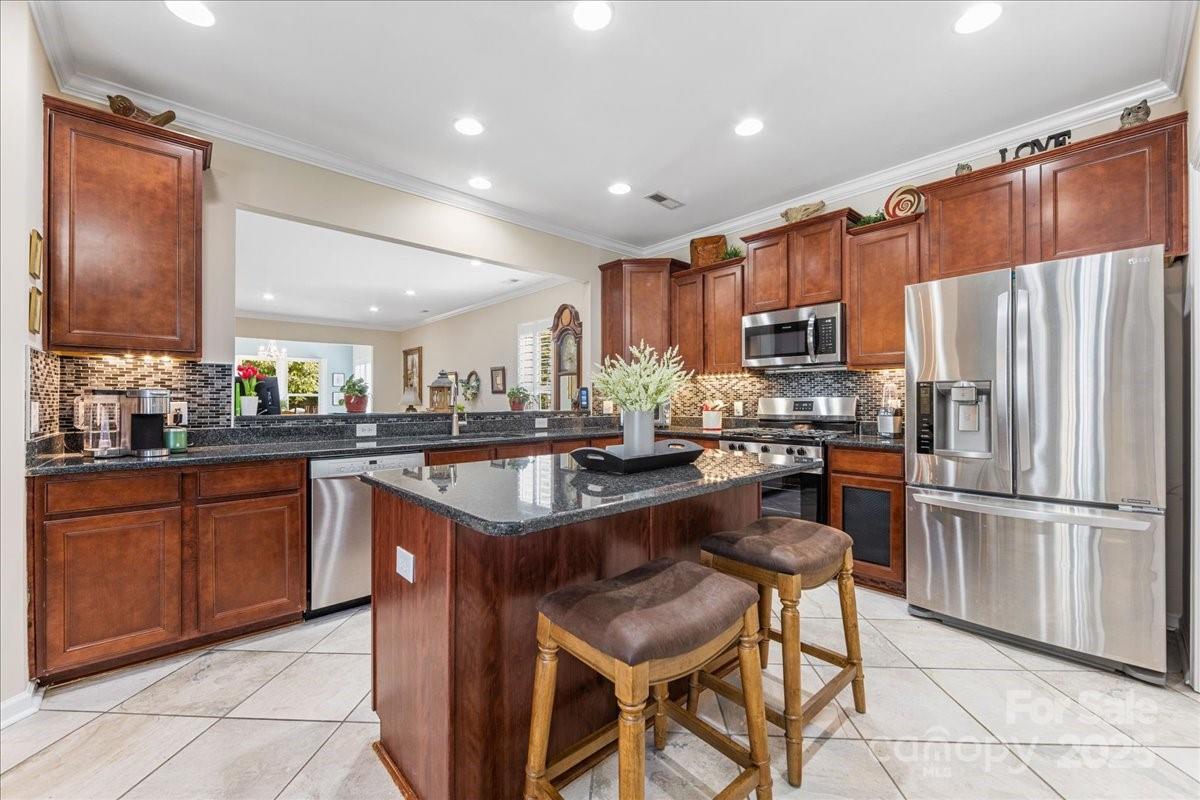2056 Kennedy Drive Fort Mill, SC 29707 - Photo 16 of 45 a kitchen with stainless steel appliances granite countertop wooden cabinets a refrigerator a sink a stove a dining table and chairs