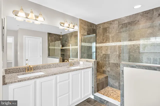 a bathroom with a granite countertop sink a toilet a mirror and shower