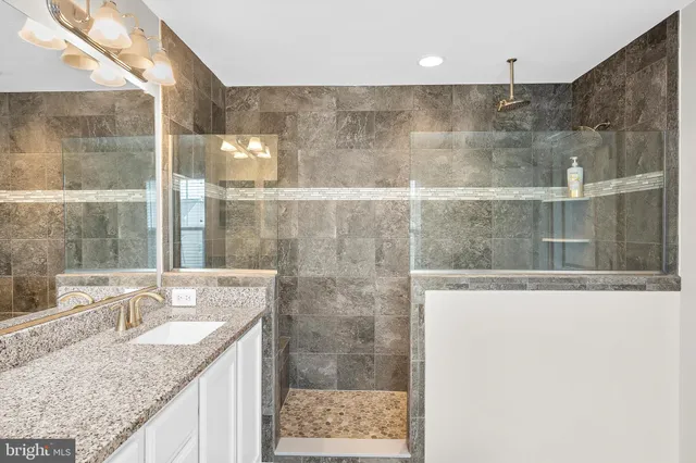 a bathroom with a granite countertop sink a mirror and shower