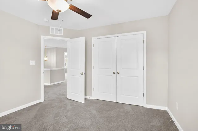 an empty room with staircase and ceiling fan