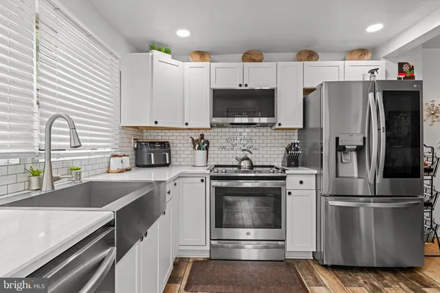 a kitchen with stainless steel appliances a refrigerator sink and white cabinets