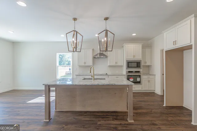 a kitchen with kitchen island granite countertop a sink cabinets and stainless steel appliances