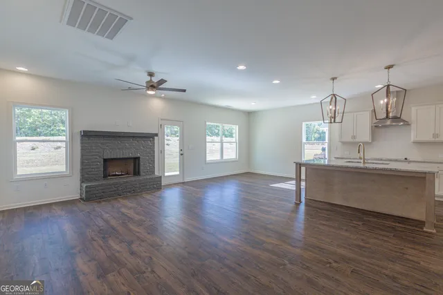 an empty room with wooden floor fireplace and windows