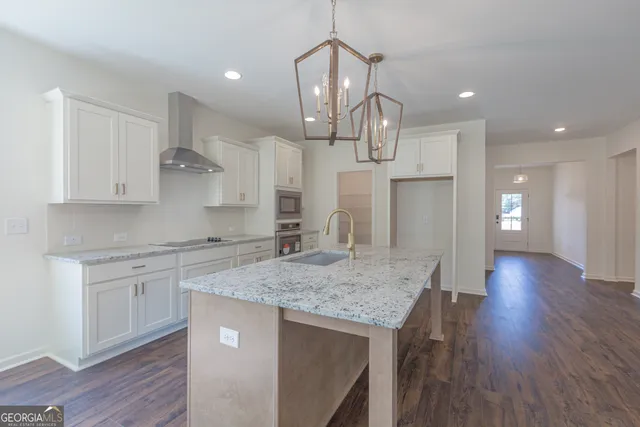 a kitchen with stainless steel appliances granite countertop a kitchen island hardwood floor sink stove and cabinets