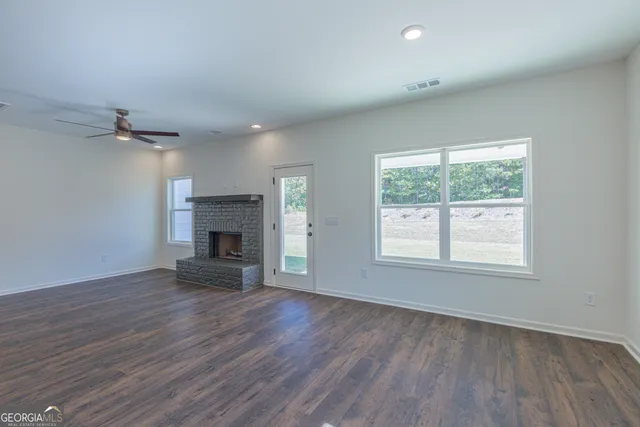 an empty room with wooden floor fireplace and windows