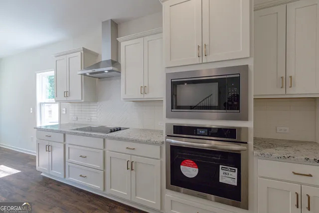 a kitchen with granite countertop white cabinets and stainless steel appliances