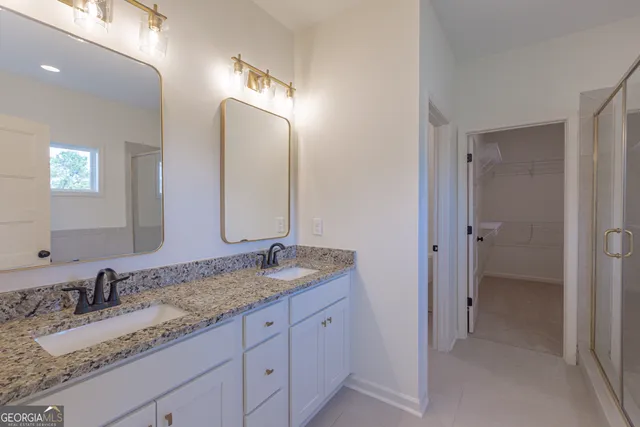 a bathroom with a granite countertop double vanity sink and a mirror