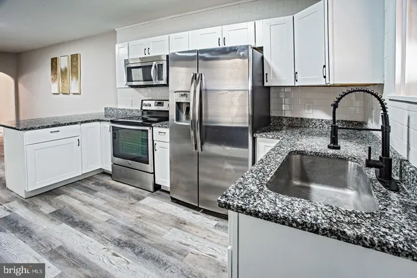a kitchen with granite countertop a sink stainless steel appliances and cabinets