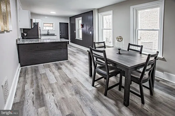 a kitchen with stainless steel appliances granite countertop a kitchen island hardwood floor sink stove dining table and chairs