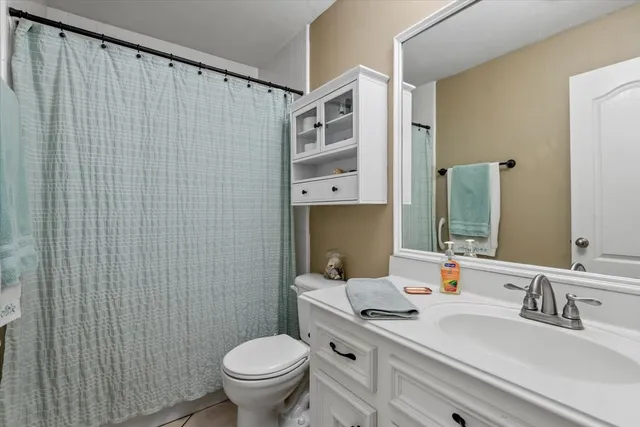 a bathroom with a granite countertop sink toilet and mirror