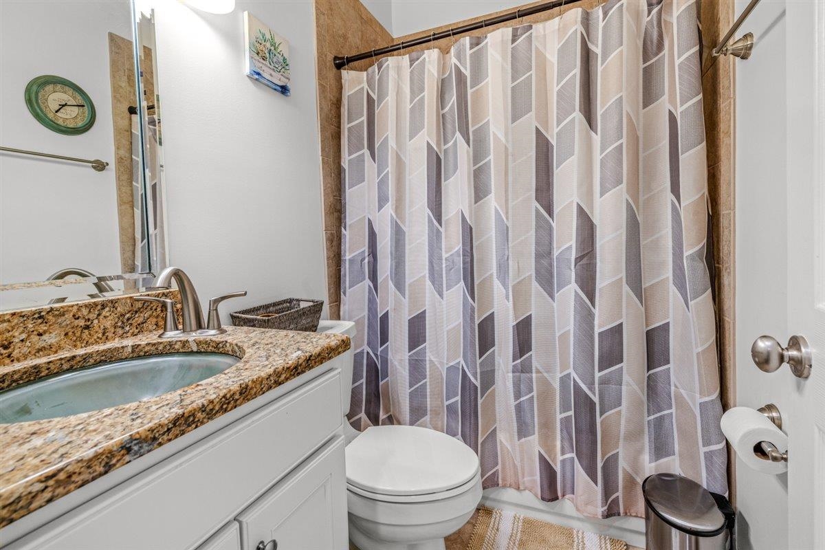 744 Southern Home Road Collierville, TN 38017 - Photo 7 of 24 Bathroom featuring a granite-look countertop with an undermount sink, white vanity cabinetry, a tiled shower surround, and a coordinating floor tile