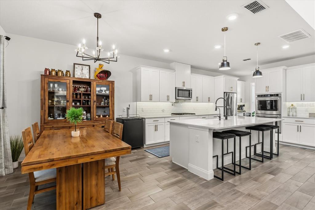 639 Primrose Willow Way Apopka, FL 32712 - Photo 17 of 70 a kitchen with stainless steel appliances kitchen island a table chairs in it and wooden floors