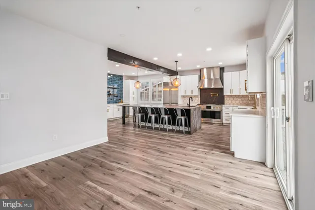 a view of a livingroom with kitchen appliances and a ceiling fan