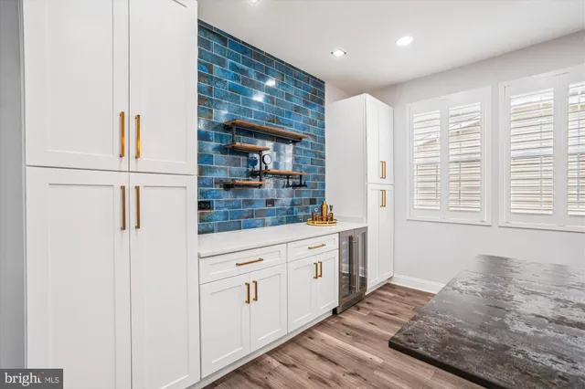 a kitchen with stainless steel appliances granite countertop a stove top oven a sink a dining table and chairs with wooden floor