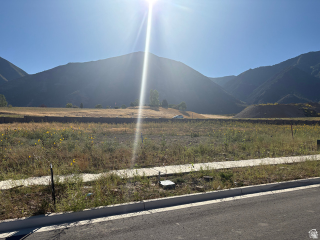 1549 South 920 East, Unit 64 Salem, UT 84653 - Photo 2 of 3 Expansive undeveloped lot featuring a paved road, concrete sidewalk, and mountain backdrop