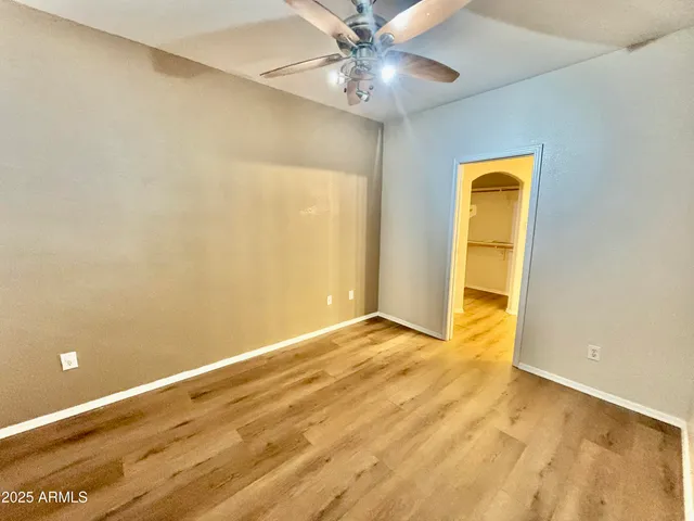 an empty room with a ceiling fan and wooden floor