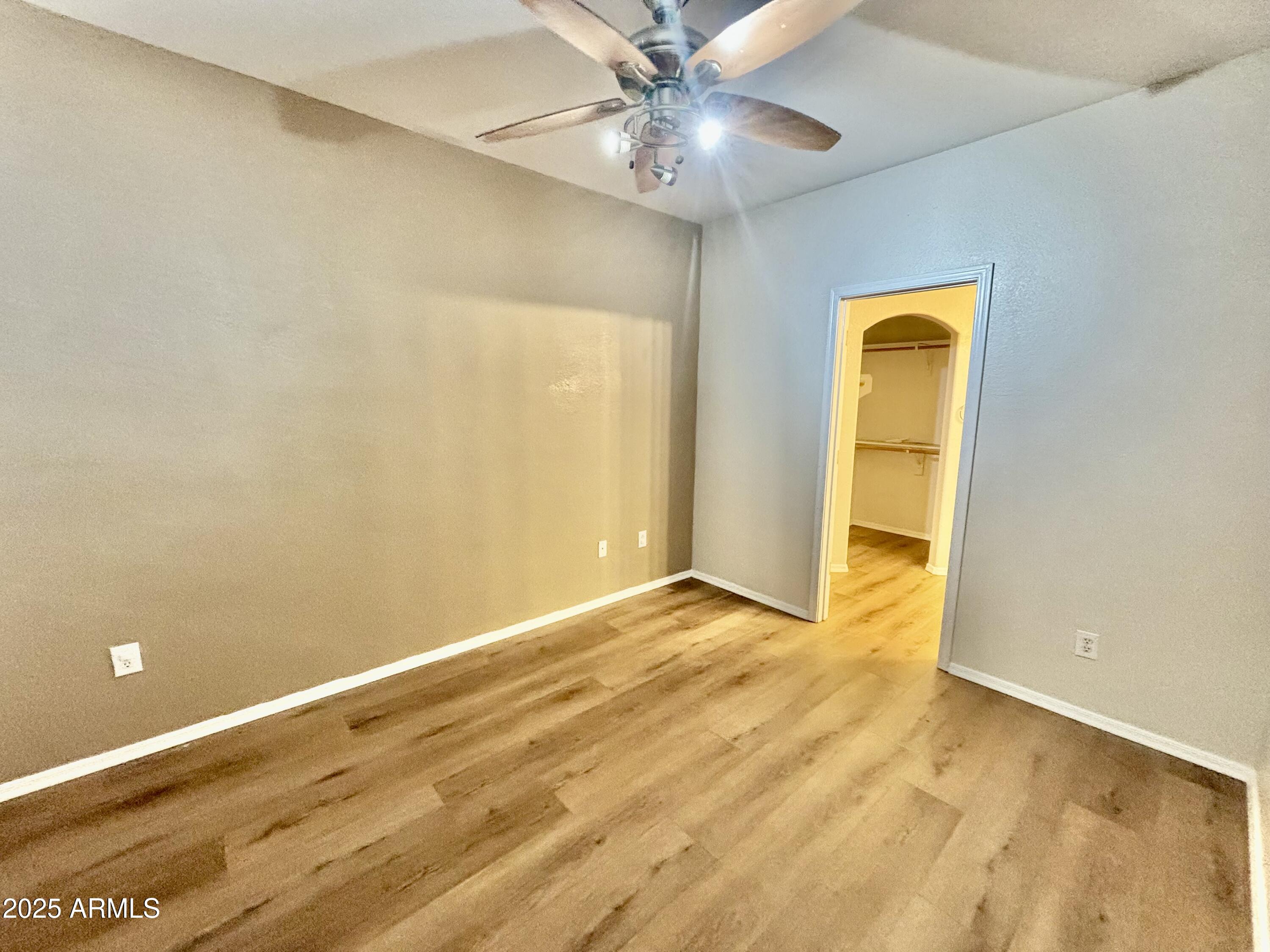 18250 North Cave Creek Road, Unit 129 Phoenix, AZ 85032 - Photo 7 of 14 an empty room with a ceiling fan and wooden floor