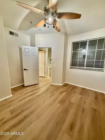 a view of an empty room with window and wooden floor