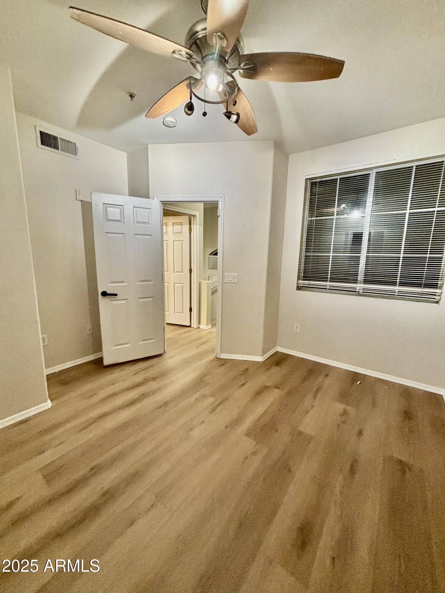18250 North Cave Creek Road, Unit 129 Phoenix, AZ 85032 - Photo 8 of 14 a view of an empty room with window and wooden floor