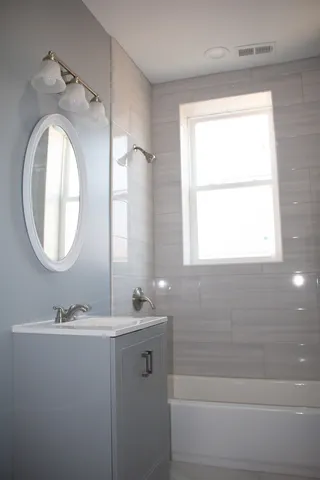 a bathroom with a granite countertop sink a mirror and a bathtub