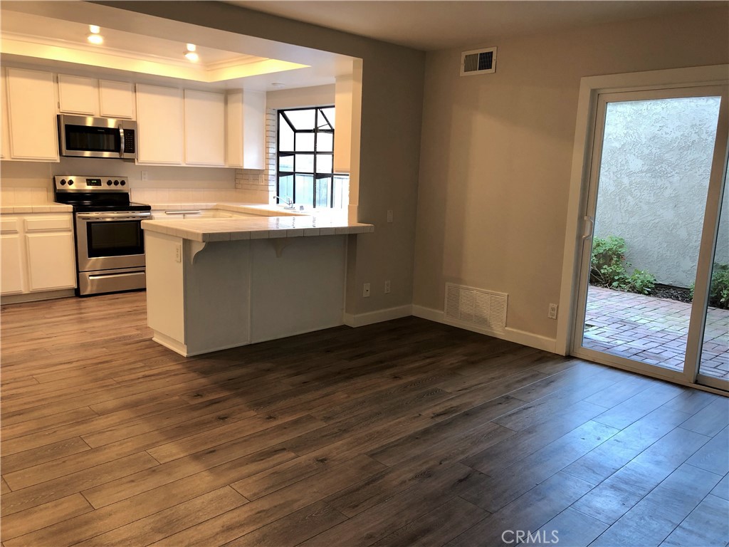 16 Prescott Irvine, CA 92620 - Photo 8 of 23 a kitchen with granite countertop wooden floors and white stainless steel appliances