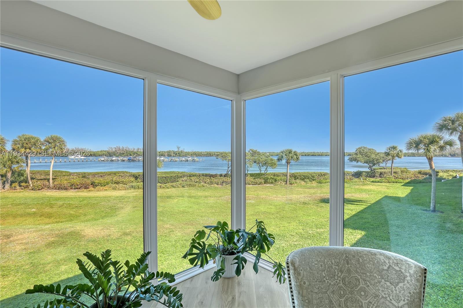 6062 Southeast Landing Way, Unit 16 Stuart, FL 34997 - Photo 12 of 35 a living room with a floor to ceiling window yard and swimming pool