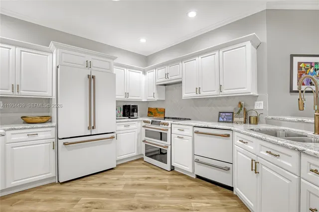 a kitchen with white cabinets white appliances and sink