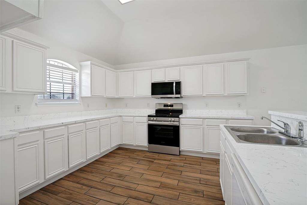 3111 Creekside Drive Sachse, TX 75048 - Photo 7 of 25 Modern kitchen featuring extensive white cabinetry, light-toned countertops, and wood-finish flooring