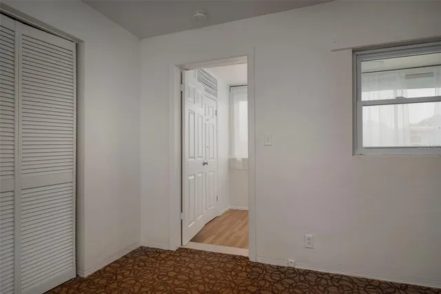 a view of an empty room with wooden floor and closet