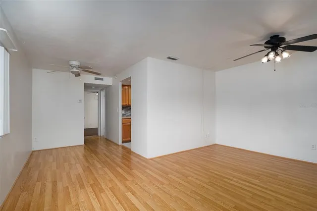 a view of a room with wooden floor and a ceiling fan