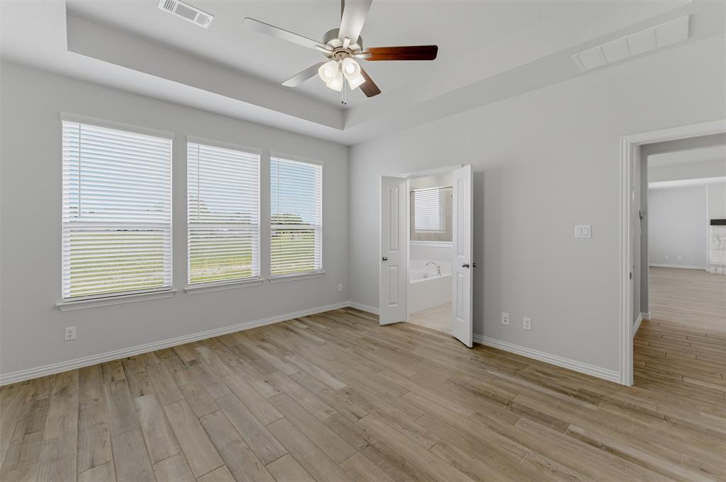 2627 Witness Tree Road Terrell, TX 75161 - Photo 15 of 27 an empty room with wooden floor chandelier fan and windows
