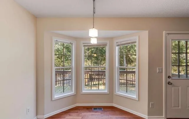 a view of an empty room with a window and wooden floor