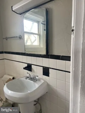 a bathroom with a sink and mirror with bathtub