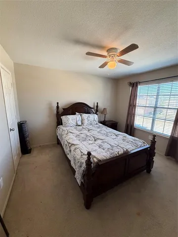 a bedroom with a large bed and a chandelier fan