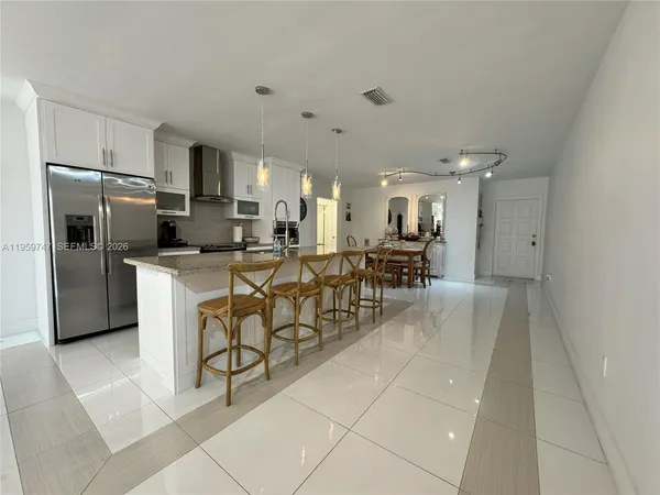 a kitchen with stainless steel appliances a refrigerator a stove a sink a dining table and chairs