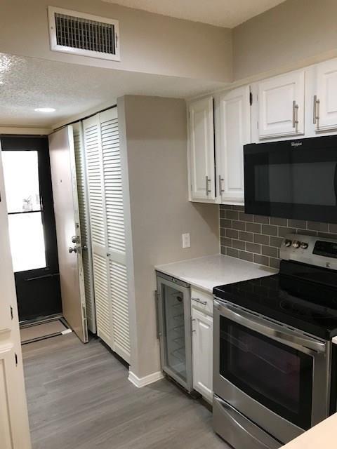 18240 Midway Road, Unit 303 Dallas, TX 75287 - Photo 6 of 22 Kitchen with stainless steel electric range, black microwave, white cabinetry, light countertops, and dark wood-style floors
