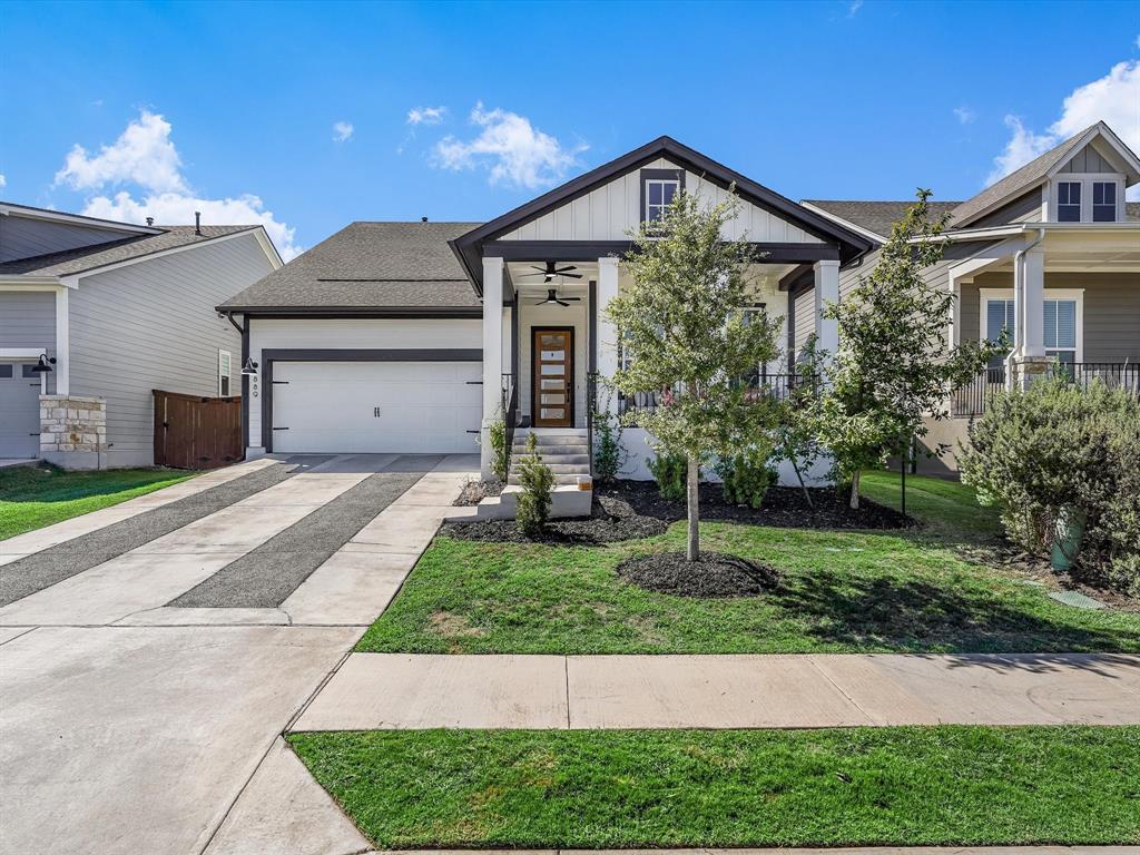View of front of property featuring concrete driveway, a front yard, and an attached garage
