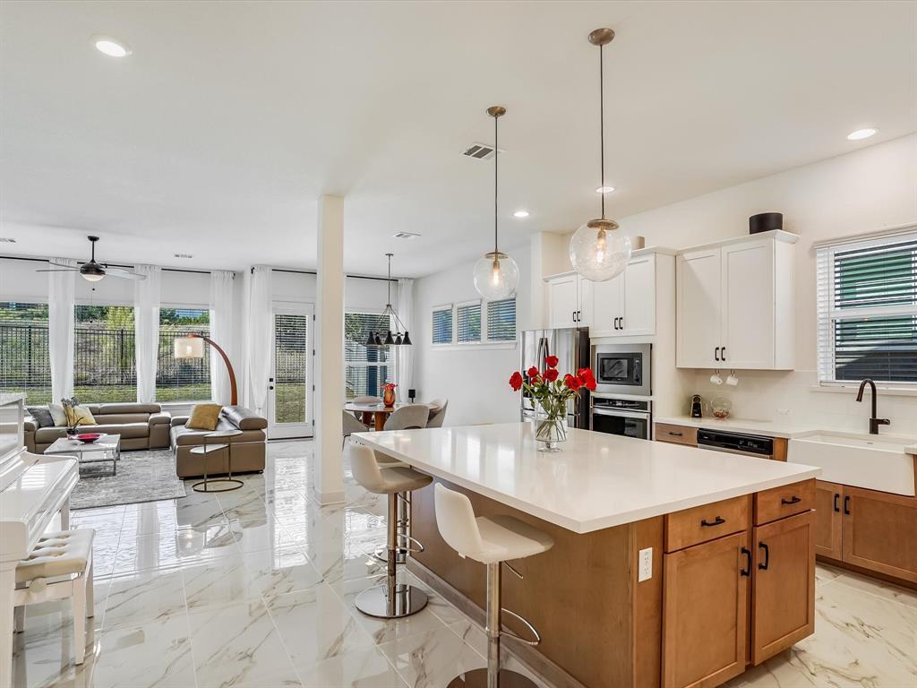 889 Hazy Hills Loop Dripping Springs, TX 78620 - Photo 20 of 20 Kitchen featuring brown cabinets, light marble finish flooring, open floor plan, recessed lighting, and a kitchen island