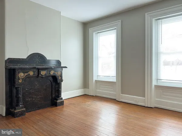 an empty room with wooden floor fireplace and windows