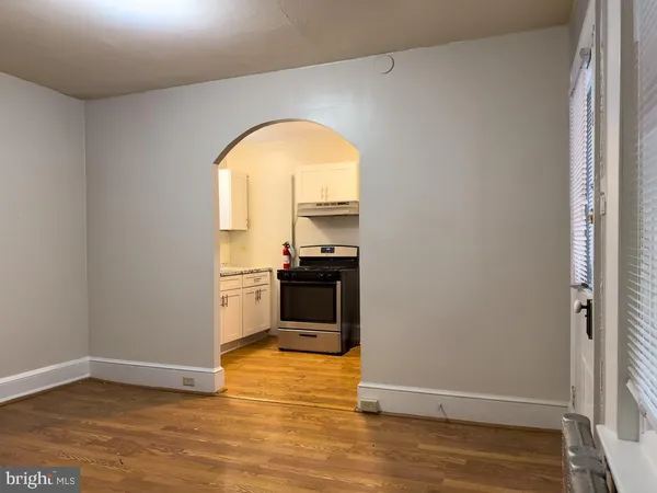 a view of empty room with wooden floor and kitchen