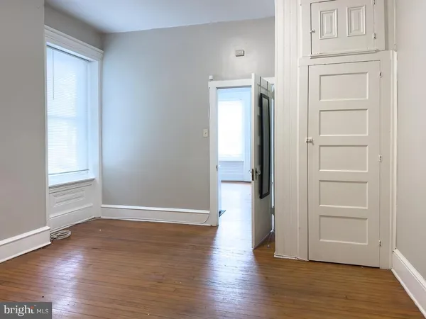 an empty room with wooden floor & closet area