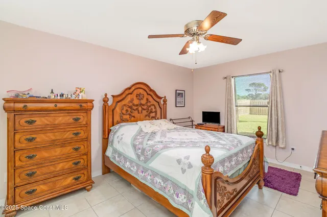 a bedroom with a bed a dresser and a chandelier