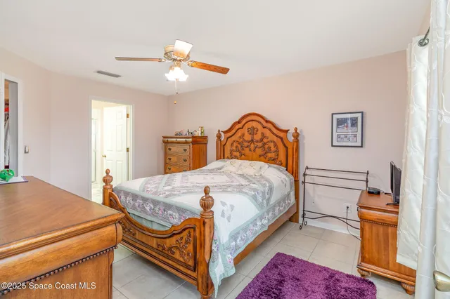 a bedroom with a bed a dresser and potted plants